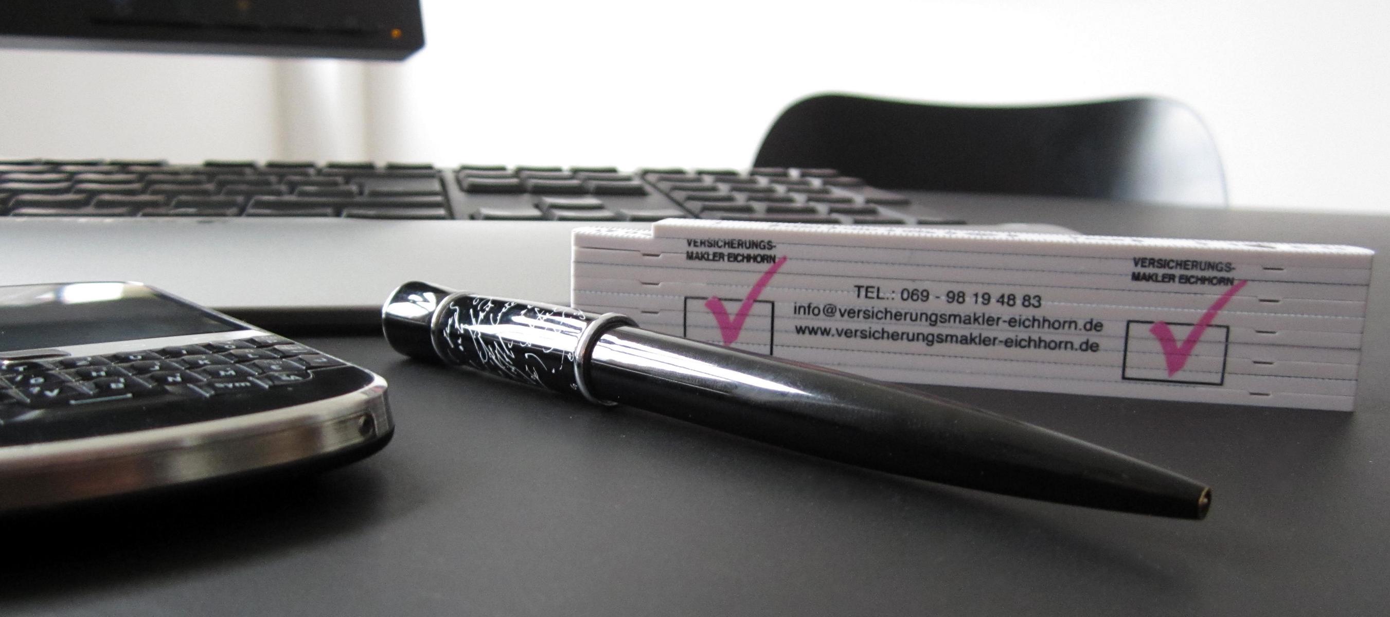Schreibtischobjekte: Handy, Stift und Visitenkarten eines Versicherungsmaklers.
